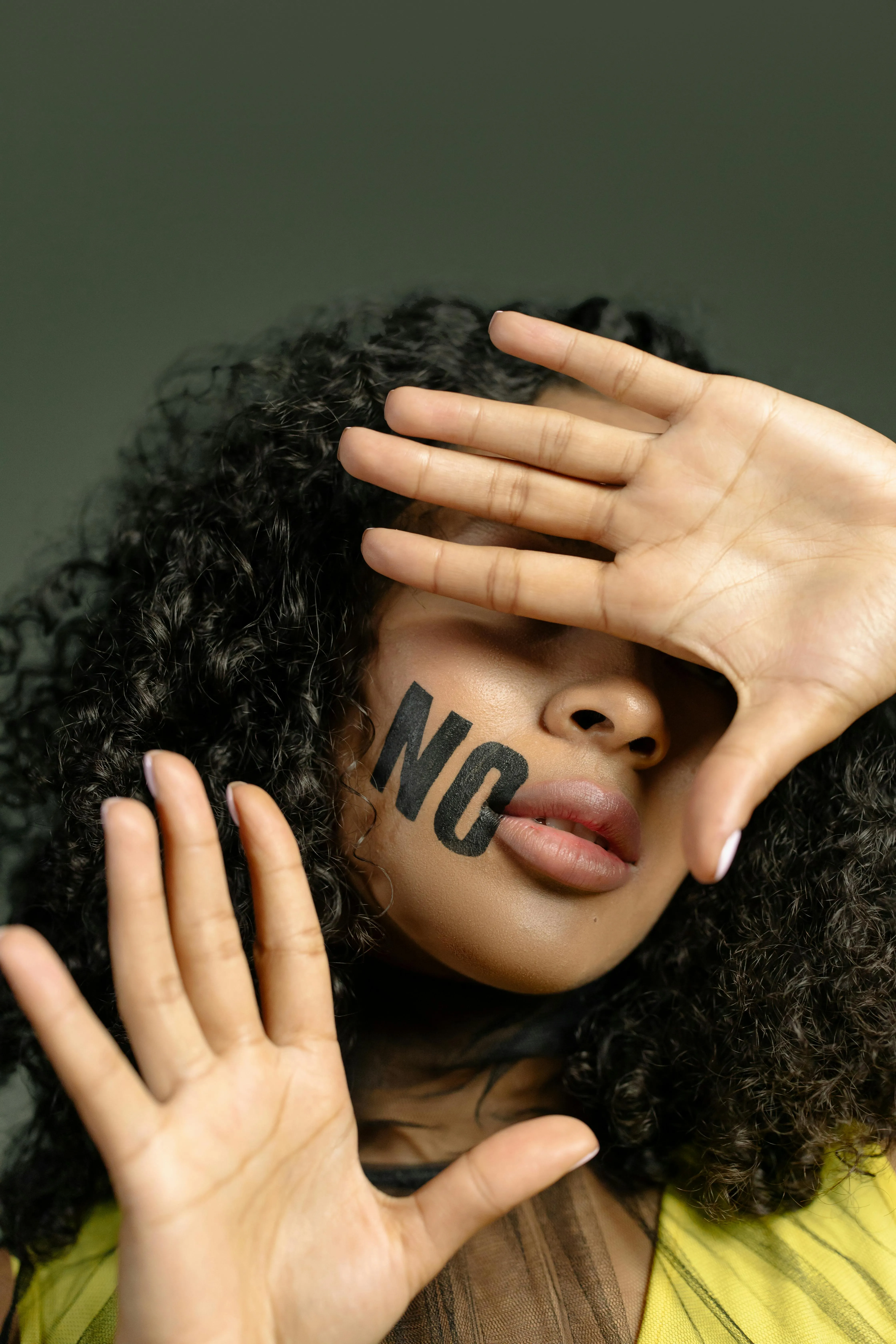 A woman holds up both hands with the word No written on her face